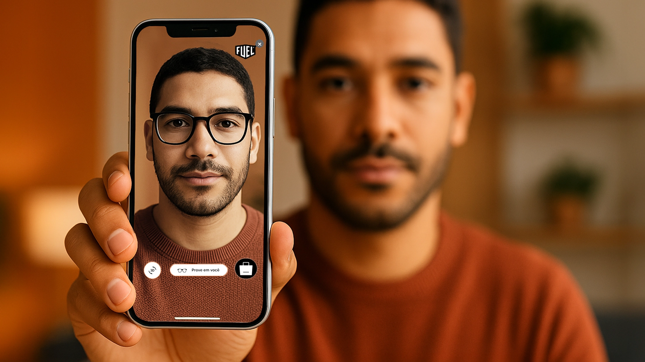 Cliente utilizando o provador virtual do site da Fuel Eyewear em um ambiente doméstico aconchegante, segurando um smartphone que exibe sua imagem com um modelo de óculos projetado em realidade aumentada, representando a experiência digital de experimentação de armações diretamente na tela.
